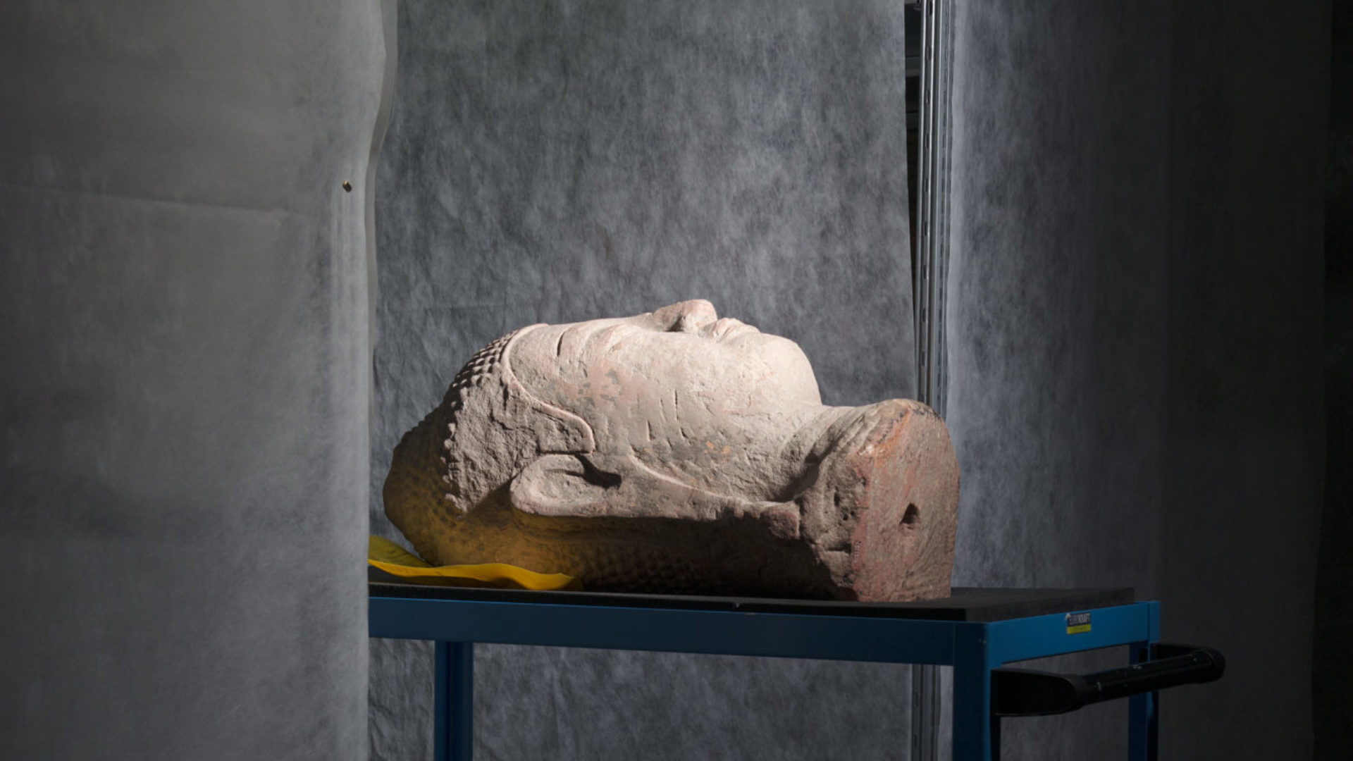 Tête de Bouddha de Thaïlande en pierre rougeâtre, photo prise au MEN de Neuchâtel  (photo Anne Golaz)
