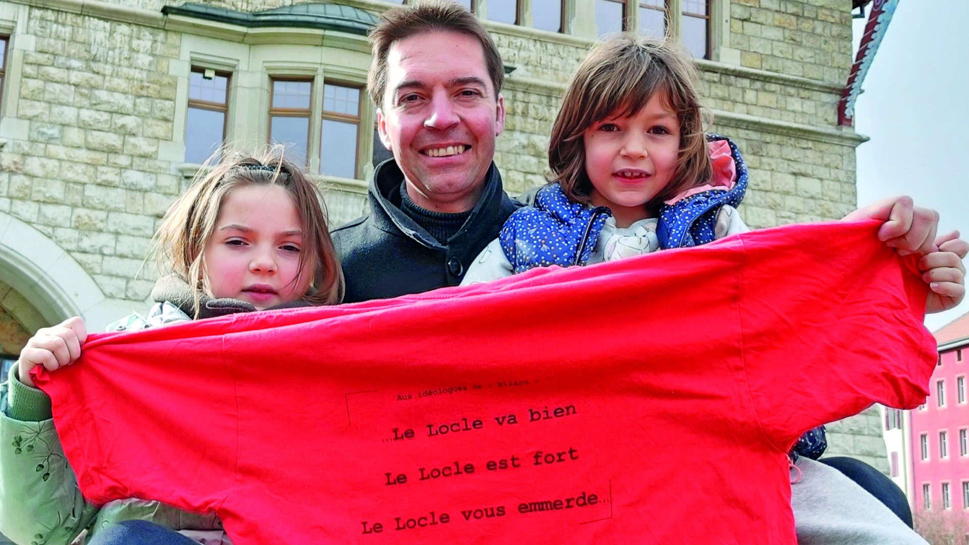 « Le Locle  vous emm… » Cédric Dupraz présente avec ses filles Camille et Elsa (à droite), le tee-shirt sorti à l’époque  « pour les idéologues de Bilanz ». (dr)