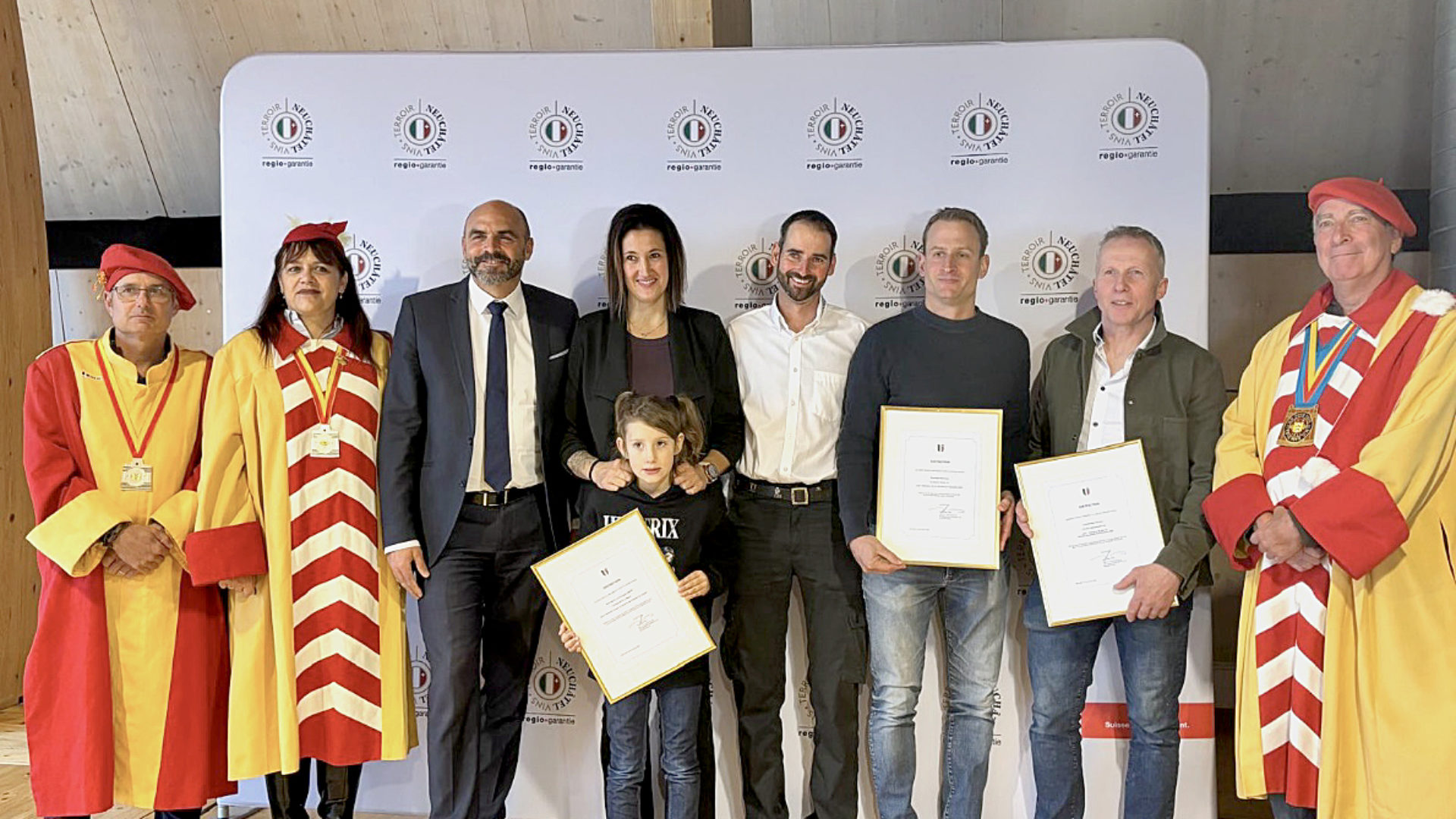 Le conseiller d'État Laurent Favre et les Vignolants aux côtés des 3 producteurs distingués : de gauche à droite, Manuela Sauser et Sébastien Maurer de la fromagerie de La Sagne, Alexandre Perrochet du domaine la Maison carrée à Auvernier et Claude-Alain Christen de la boucherie Christen Delicatessen à La Chaux-de-Fonds (Photo EM)